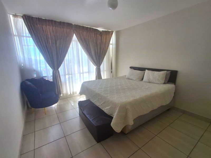 A bedroom featuring tiled flooring and a large floor-to-ceiling window that allows for ample natural light.