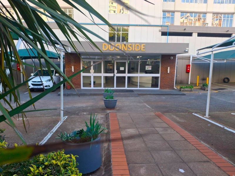 Front entrance and parking area of the Doonside apartment building, featuring paved driveway and covered parking bays.