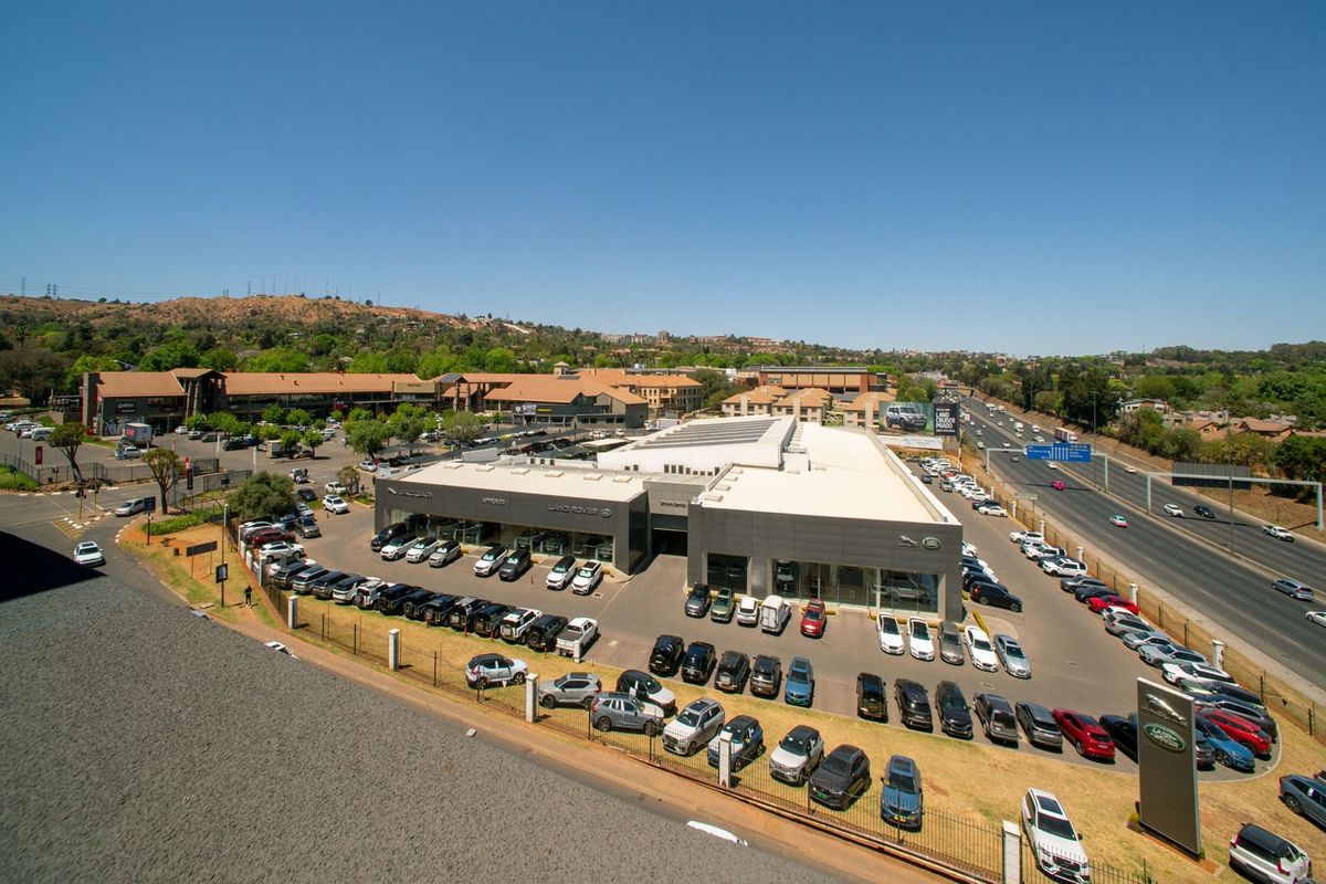 An aerial view of a commercial automotive dealership facility with extensive paved parking and surrounding infrastructure.