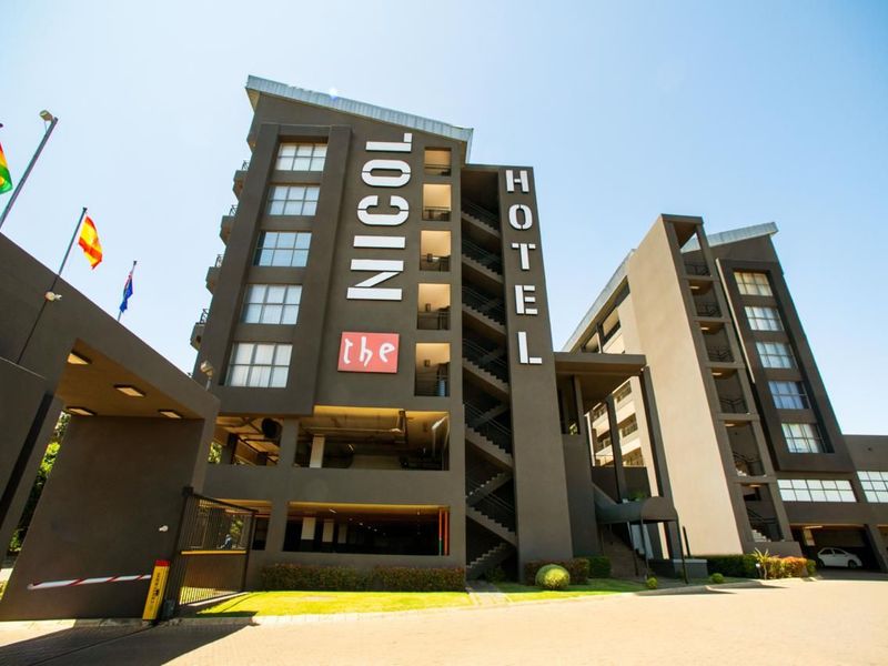 A modern multi-story hotel building featuring a prominent facade, external staircases, and a secure ground-level parking area.
