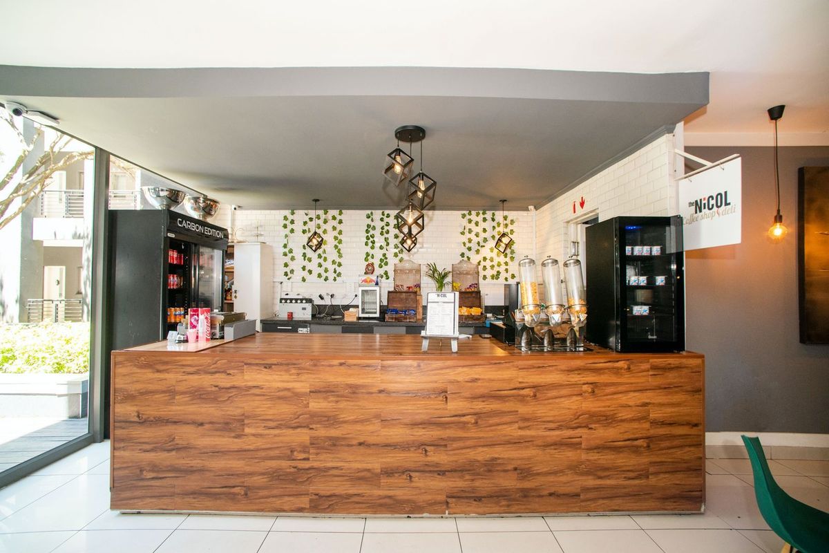 A commercial-style service counter featuring a wood-look finish, subway tile backsplash, and modern pendant lighting in a well-maintained deli or cafe space.