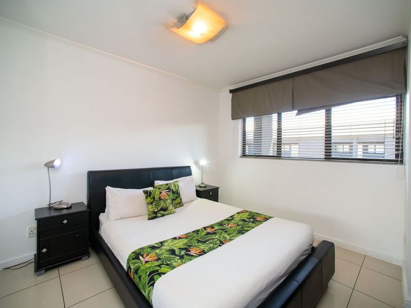 A well-maintained bedroom featuring tiled flooring, neutral walls, and window blinds, providing a clean and functional living space.