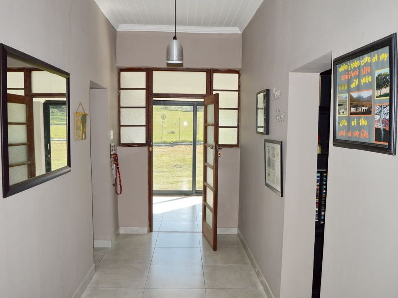 A bright, tiled entrance hallway featuring a timber-framed glass door and sidelights, leading directly to the exterior garden area.