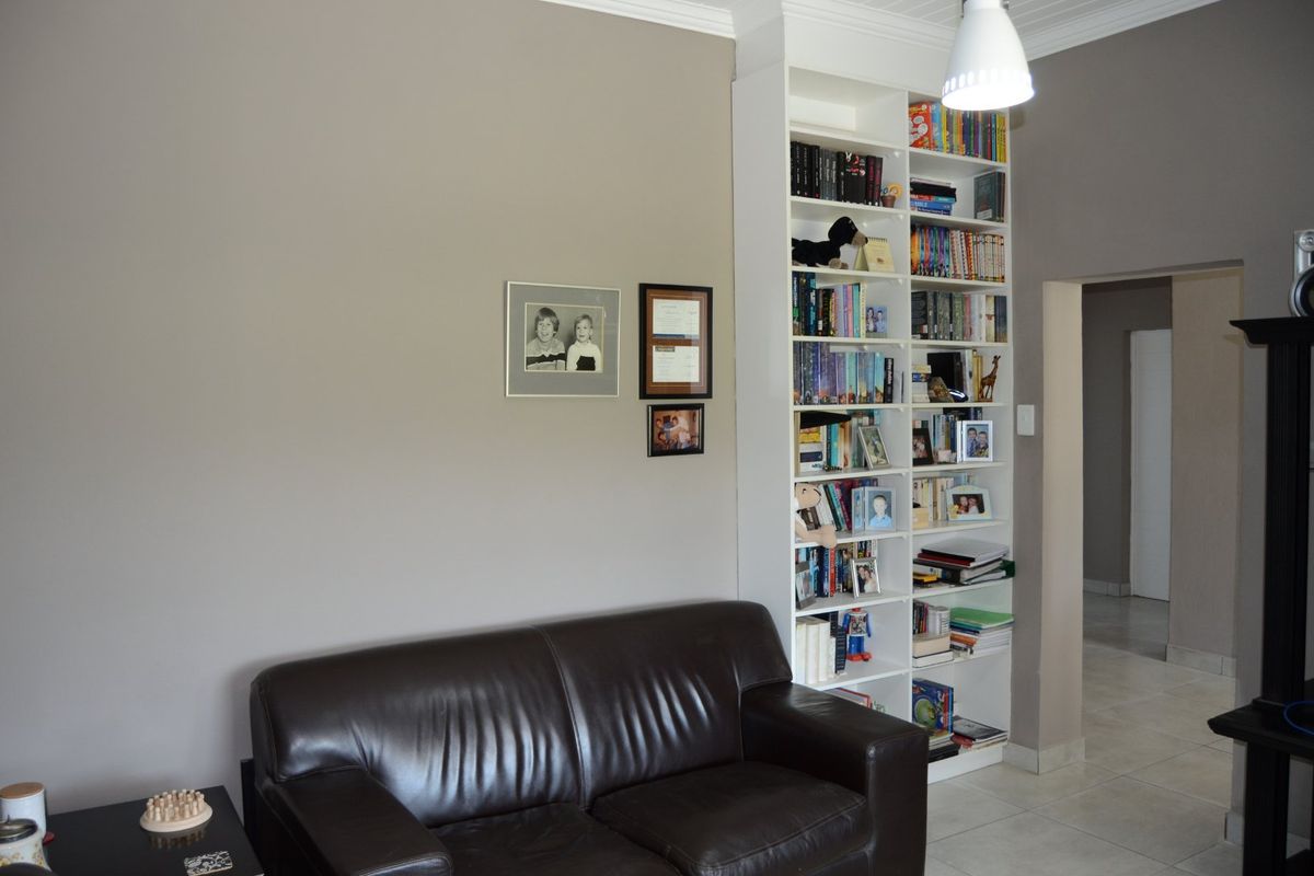 A living room area featuring a tall, white built-in shelving unit and neutral wall tones with tiled flooring.