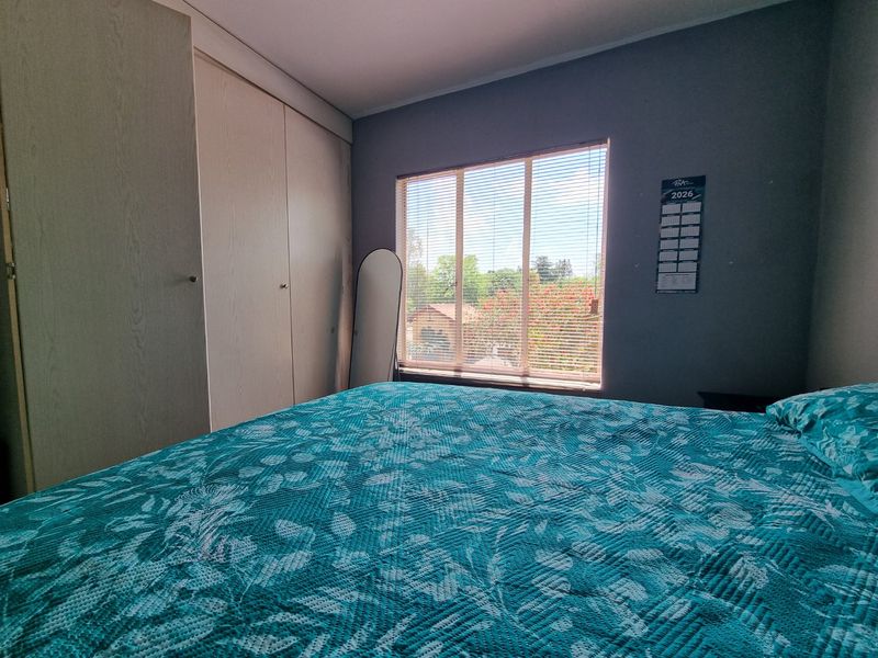 A bedroom featuring built-in cupboards and venetian blinds, offering a functional space with natural light.