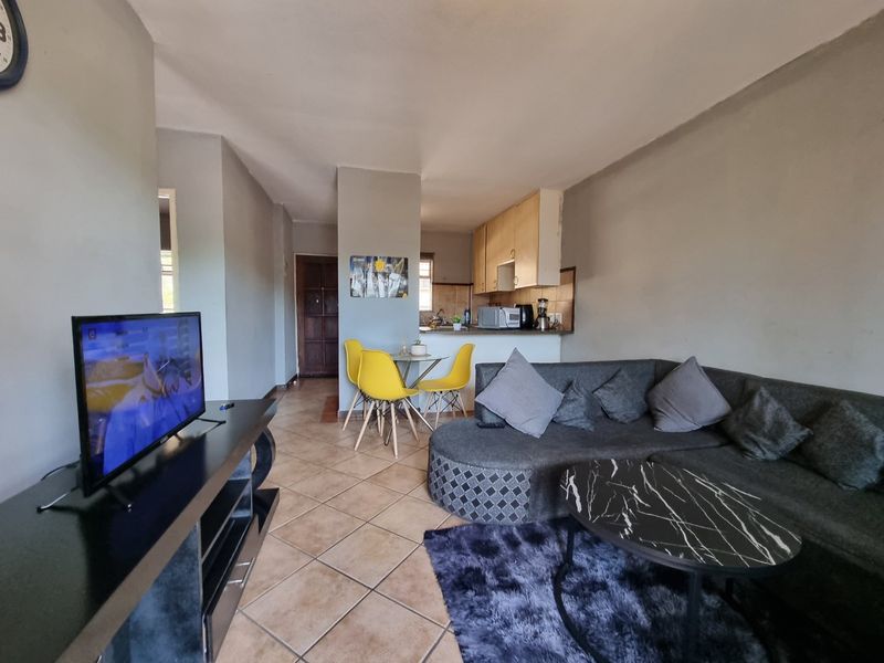 Open plan living and dining area featuring tiled flooring and a compact kitchen with built-in cabinetry.
