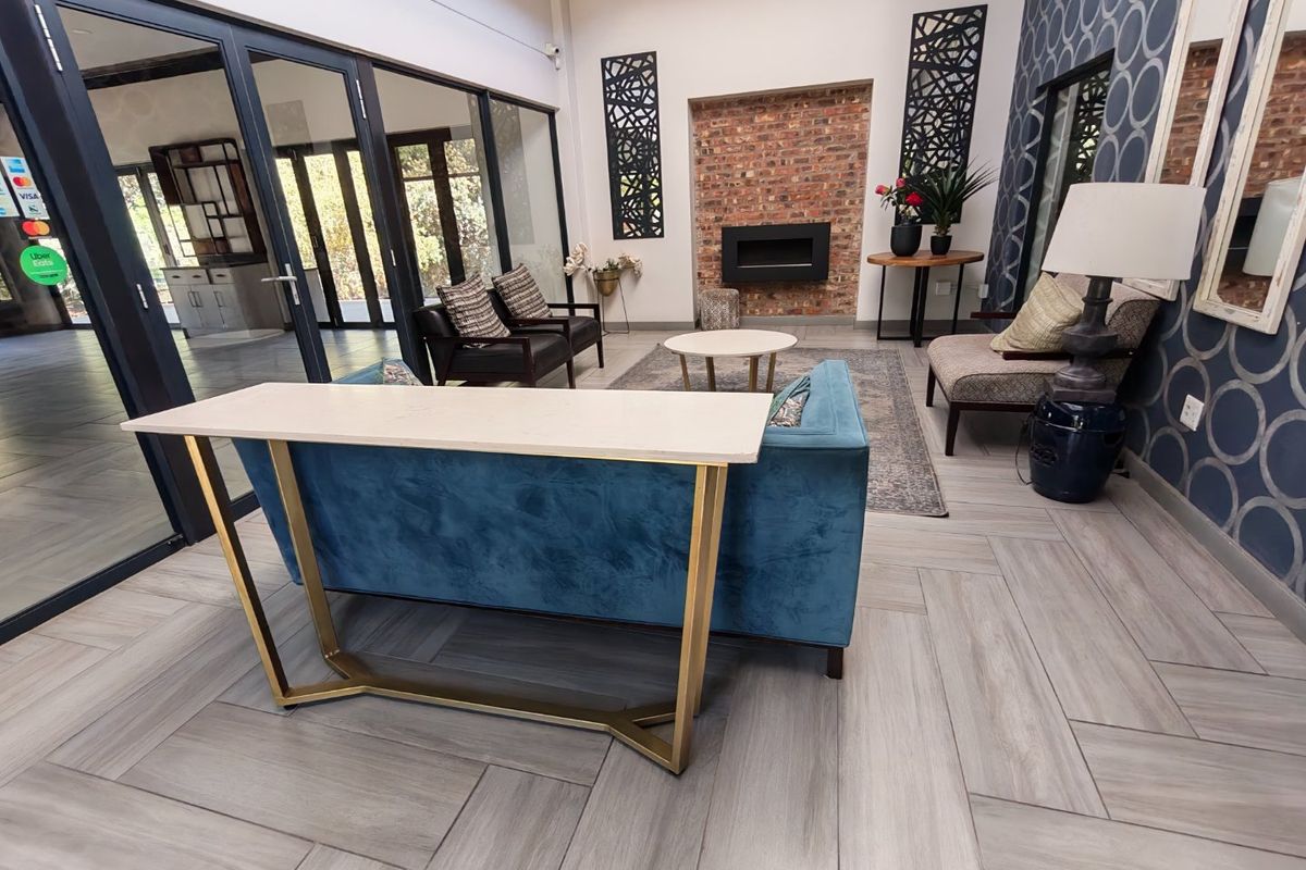Spacious living room featuring a modern built-in fireplace, exposed brick accent wall, and elegant herringbone tile flooring with large glass sliding doors.