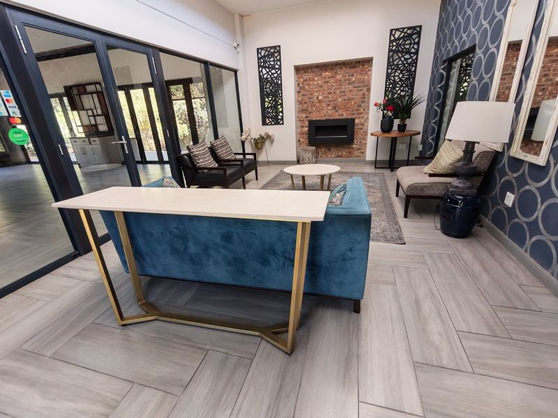 Spacious living room featuring a modern built-in fireplace, exposed brick accent wall, and elegant herringbone tile flooring with large glass sliding doors.