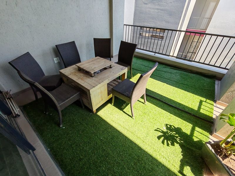 A private balcony featuring artificial grass flooring and a metal safety balustrade, providing an outdoor space for relaxation.