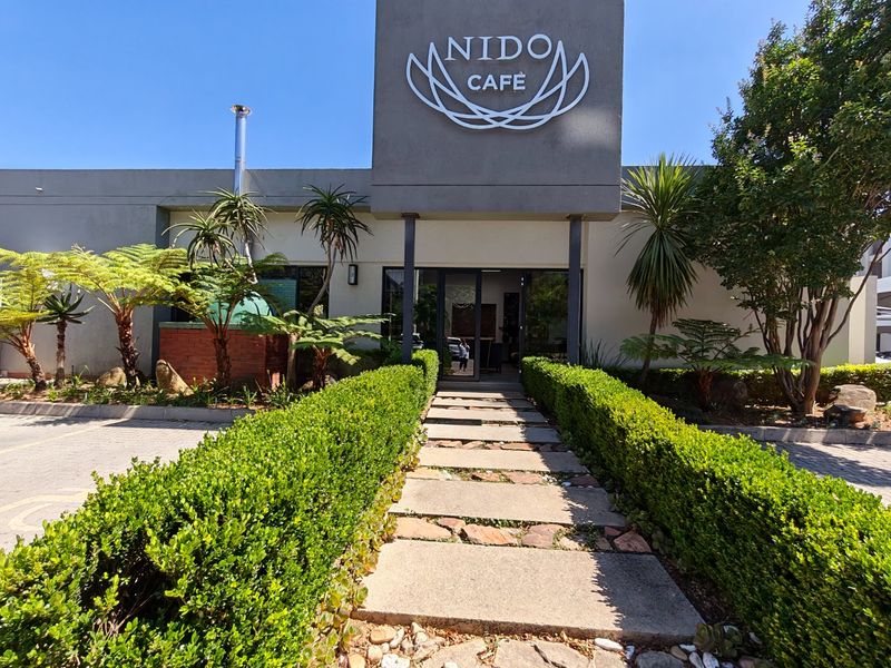 Front entrance view of the property featuring a paved walkway lined with manicured hedges and a prominent building facade.