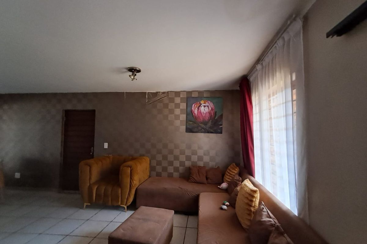 A living room featuring tiled flooring and a feature wall with visible wallpaper damage, offering potential for cosmetic updates and modernization.