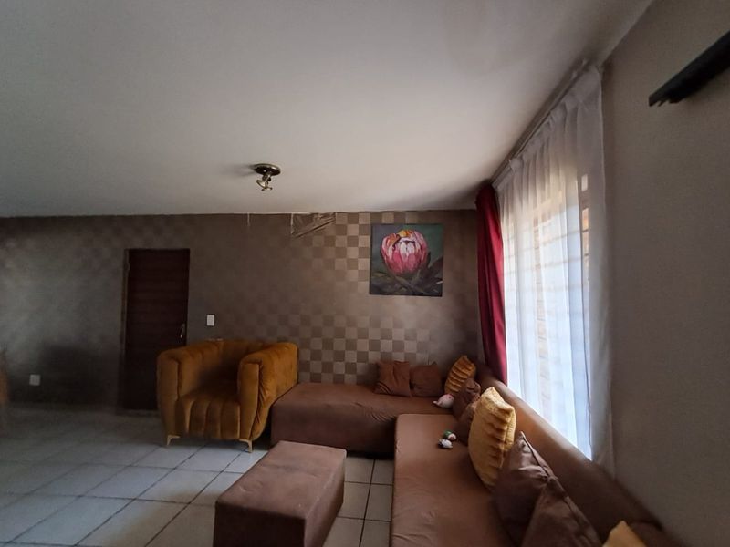 A living room featuring tiled flooring and a feature wall with visible wallpaper damage, offering potential for cosmetic updates and modernization.
