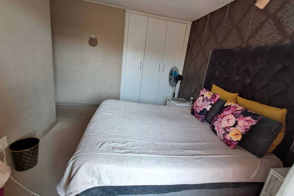 A bedroom featuring a built-in wardrobe and a textured accent wall.