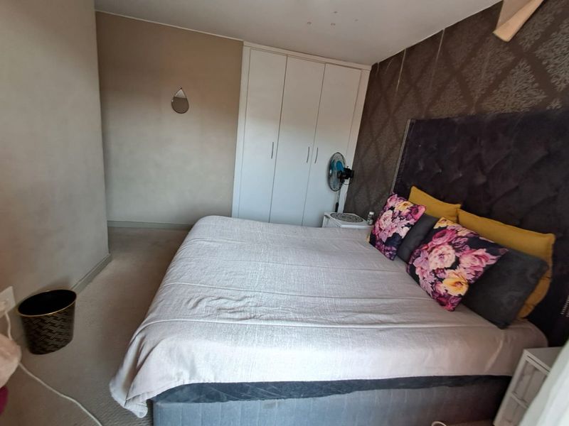 A bedroom featuring a built-in wardrobe and a textured accent wall.