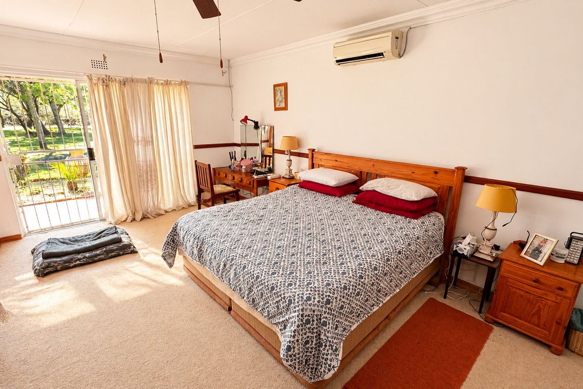 Spacious bedroom featuring neutral carpeting, crown molding, a split-system air conditioner, and a sliding glass door providing direct access to the garden.