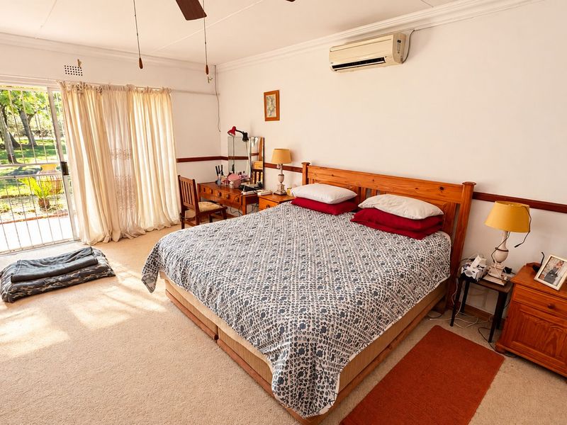 Spacious bedroom featuring neutral carpeting, crown molding, a split-system air conditioner, and a sliding glass door providing direct access to the garden.