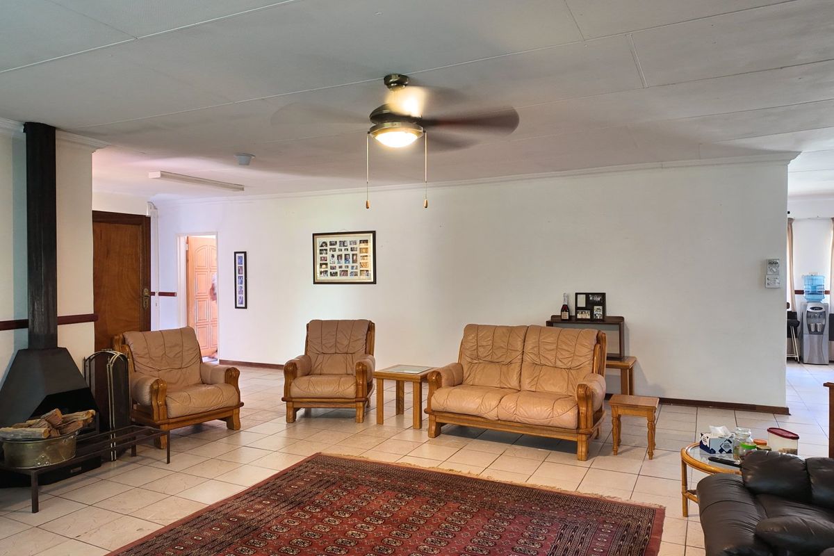 Spacious living room featuring a freestanding fireplace, tiled flooring, and a ceiling fan, offering a comfortable and functional layout.