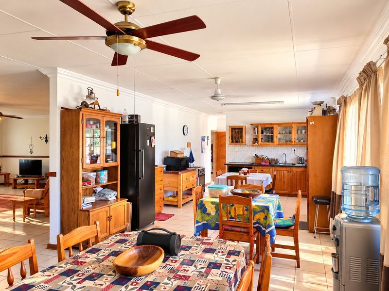 Spacious open-plan living and dining area featuring tiled floors, ceiling fans, and a functional kitchen with built-in cabinetry.