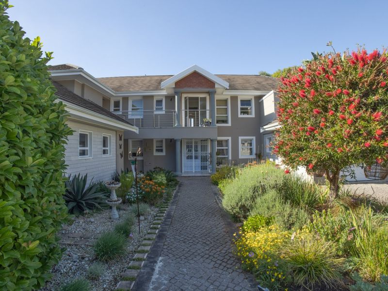 A well-maintained front exterior view of the apartment building featuring a paved walkway, landscaped garden, and a covered balcony entrance.