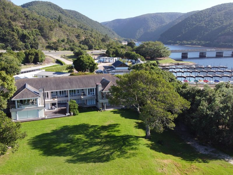 Aerial view of a waterfront property featuring a large lawn, multi-level balconies, and direct access to the marina and surrounding landscape.