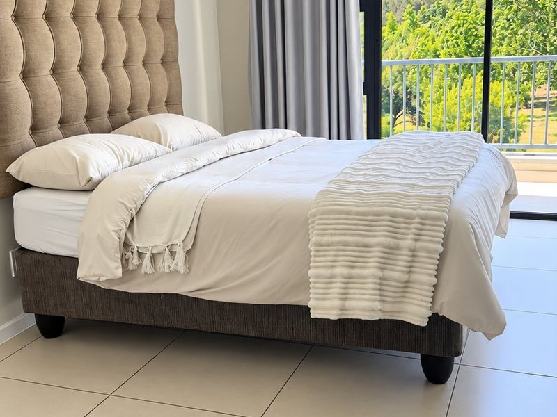 A bright bedroom featuring large format floor tiles, a coved ceiling, and a sliding glass door providing direct access to a private balcony.