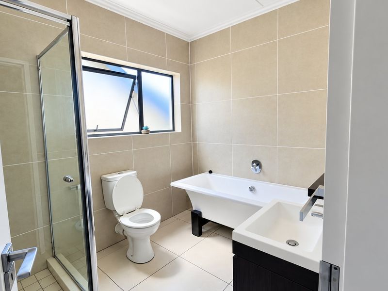 Modern bathroom featuring a freestanding bathtub, separate shower enclosure, vanity basin, and neutral floor-to-ceiling wall tiling.