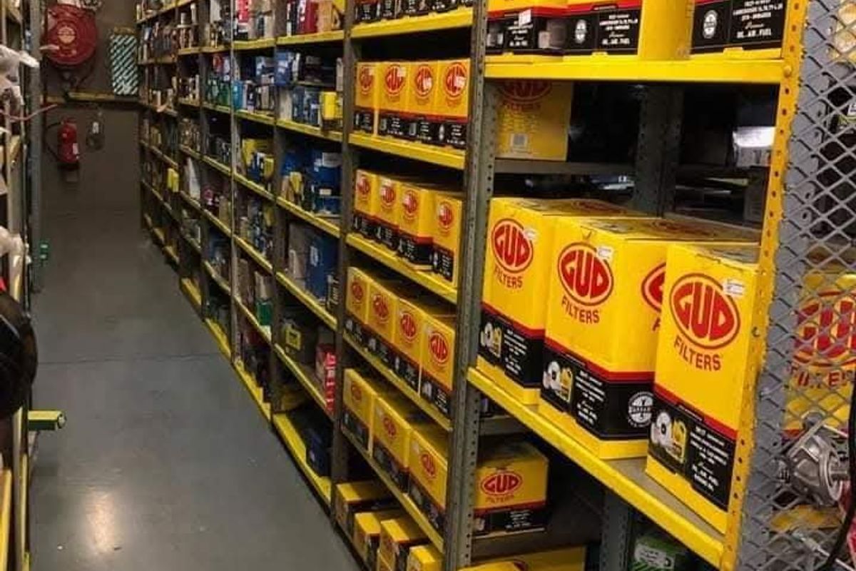 A commercial utility storage area featuring extensive industrial metal shelving units, fire safety equipment, and durable epoxy flooring.