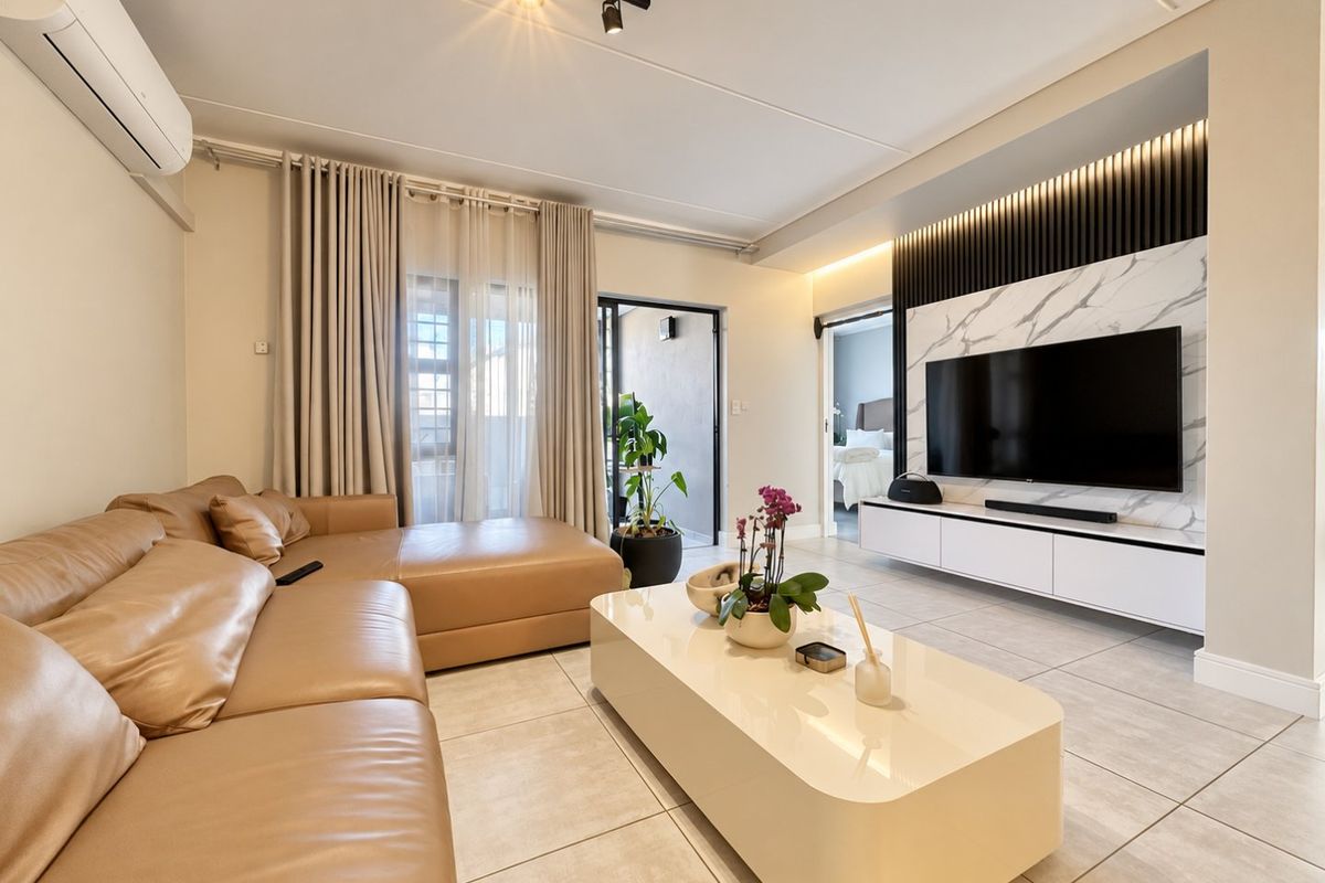 Modern living room featuring tiled floors, a sleek built-in media wall with marble-look and timber accents, track lighting, and a split-system air conditioner.