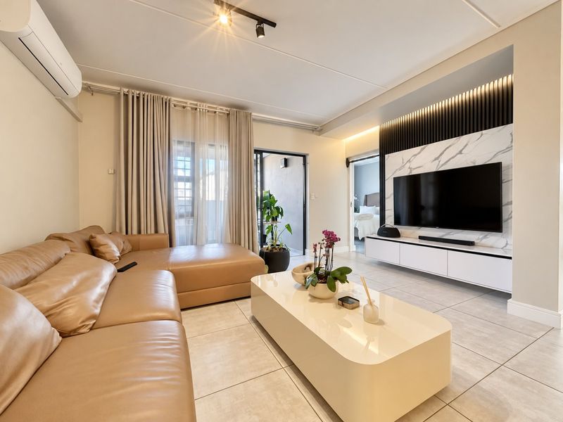 Modern living room featuring tiled floors, a sleek built-in media wall with marble-look and timber accents, track lighting, and a split-system air conditioner.