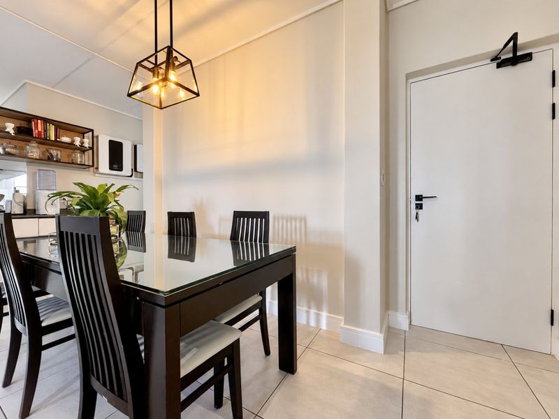 A bright dining area featuring modern tiled flooring, a stylish pendant light fixture, and built-in wall shelving, creating a clean and functional space.