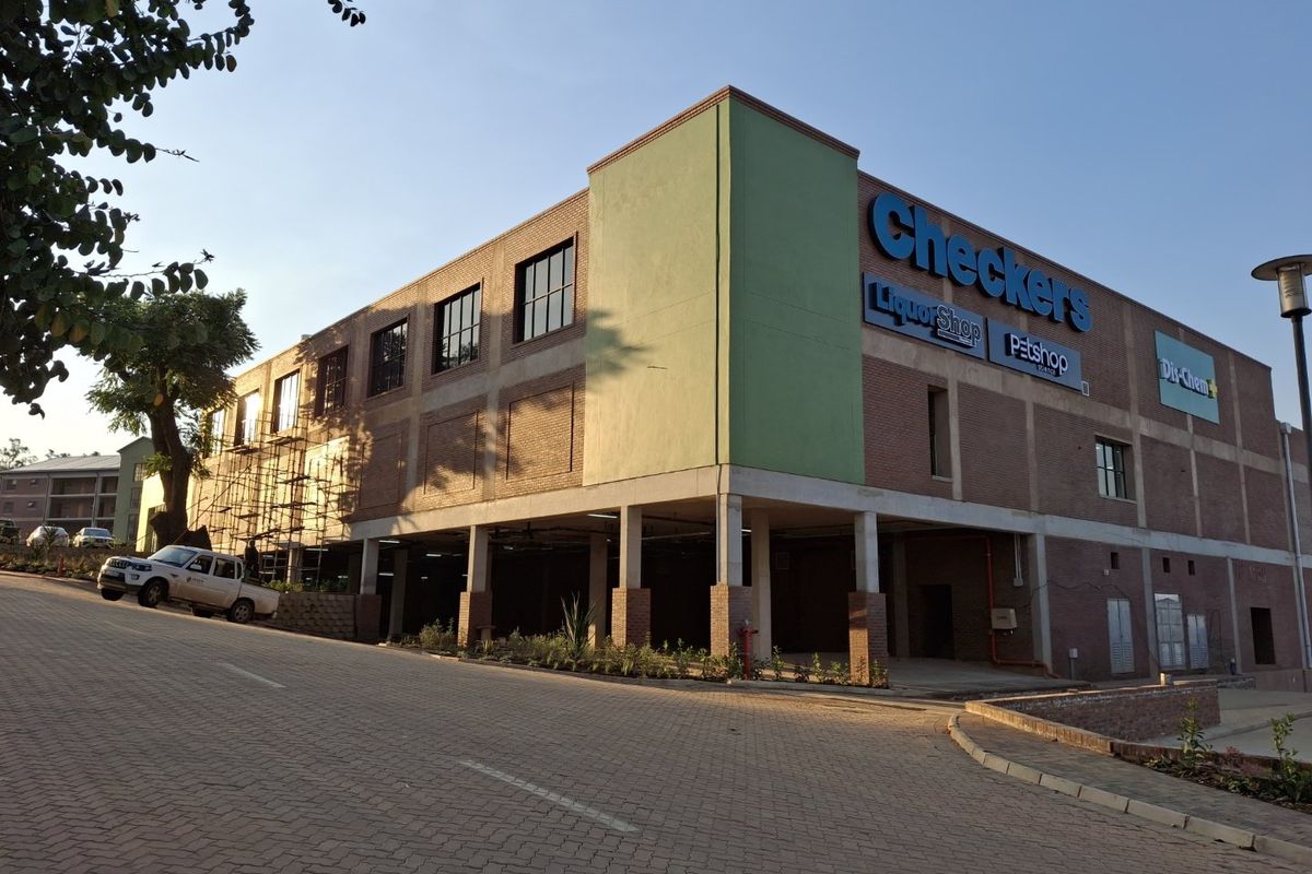 Exterior view of a commercial apartment complex featuring a brick facade, covered parking area, and prominent retail signage.