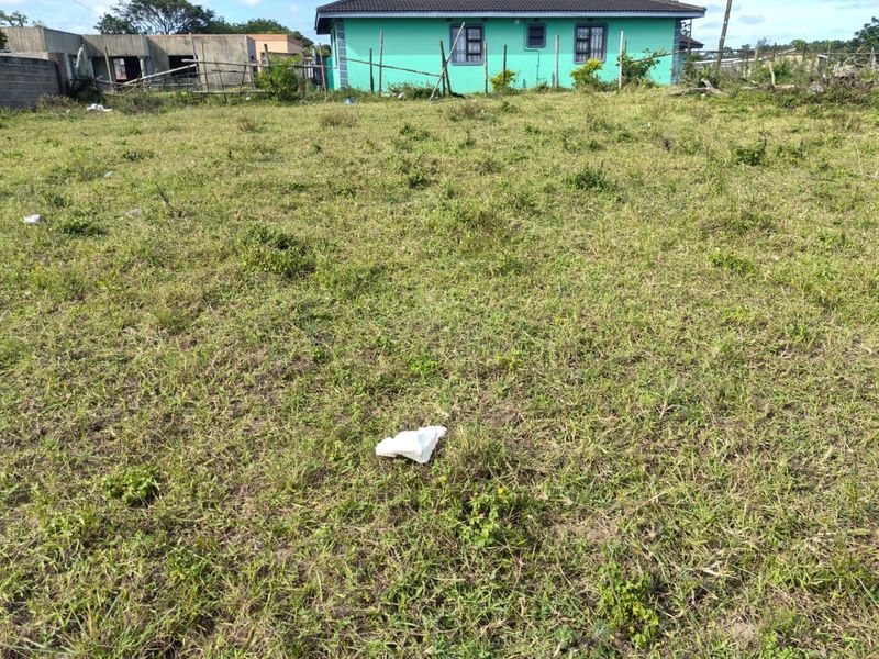 A vacant residential plot of land featuring a grass lawn and boundary fencing, situated in a developed neighborhood.