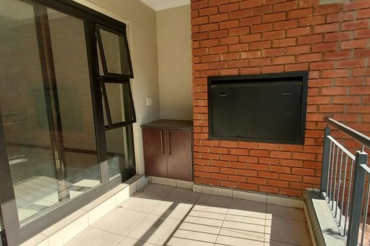 Covered balcony featuring a built-in braai, tiled flooring, and a built-in storage cabinet, providing a functional outdoor entertainment space.