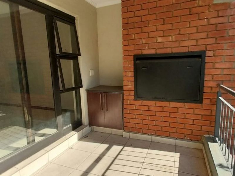 Covered balcony featuring a built-in braai, tiled flooring, and a built-in storage cabinet, providing a functional outdoor entertainment space.