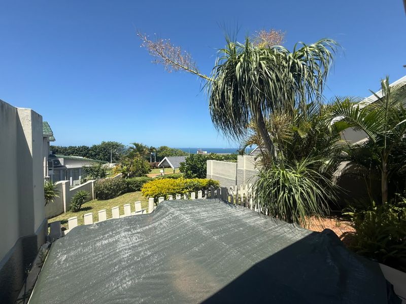 A scenic outdoor view overlooking the surrounding estate grounds with a glimpse of the ocean in the distance.