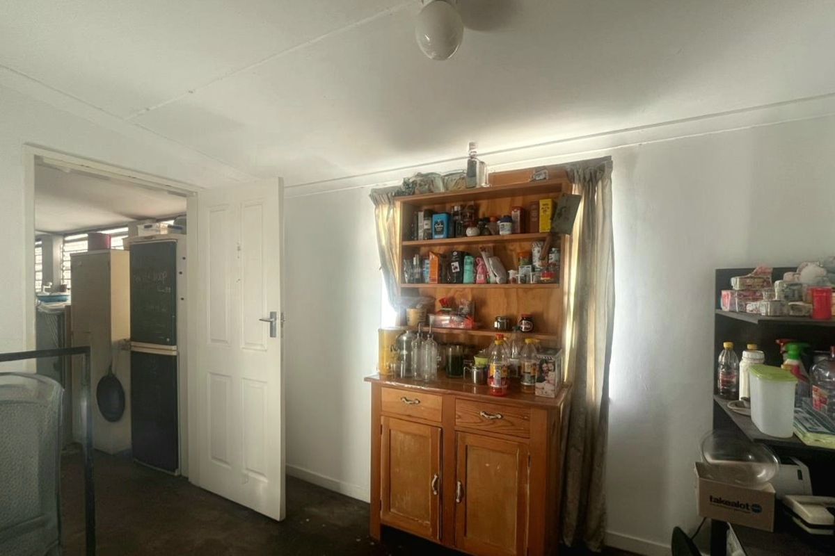 A simple living area featuring plain white walls, a ceiling light fixture, and an internal door leading to an adjacent room.