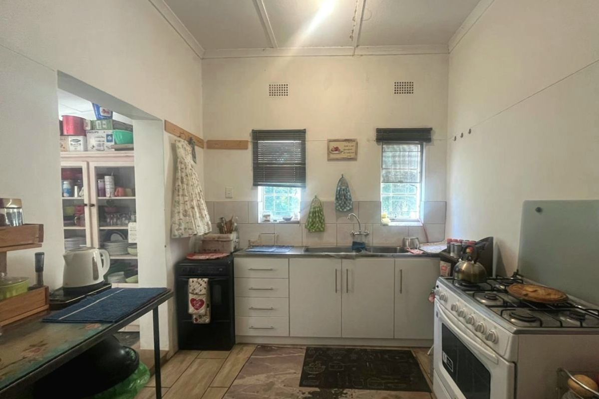 A functional kitchen featuring built-in cabinetry, a stainless steel sink, and a gas stove, with tiled flooring and splashbacks throughout.