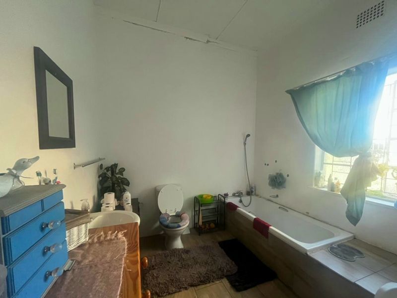A functional bathroom featuring a bathtub, toilet, and tiled flooring, requiring some cosmetic attention to the ceiling and wall finishes.