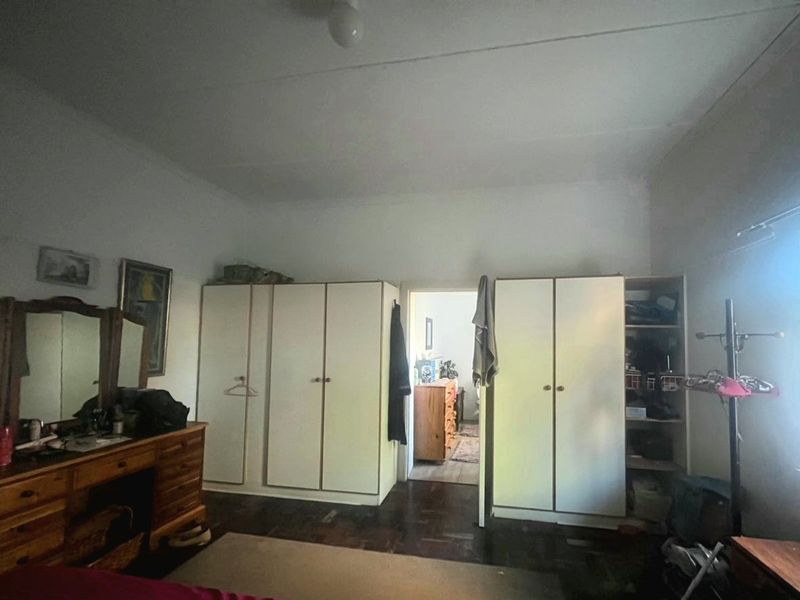 Bedroom featuring built-in cupboards and parquet flooring, offering a functional layout with potential for cosmetic updates to enhance the space.