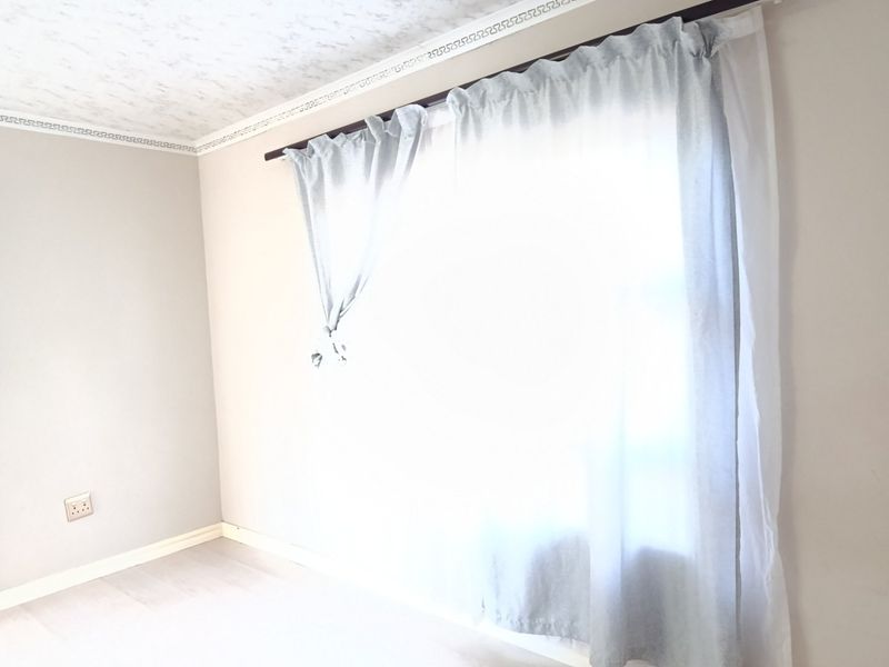 A bright, empty bedroom featuring neutral wall finishes, ceiling cornicing, and a window with installed curtain rod.