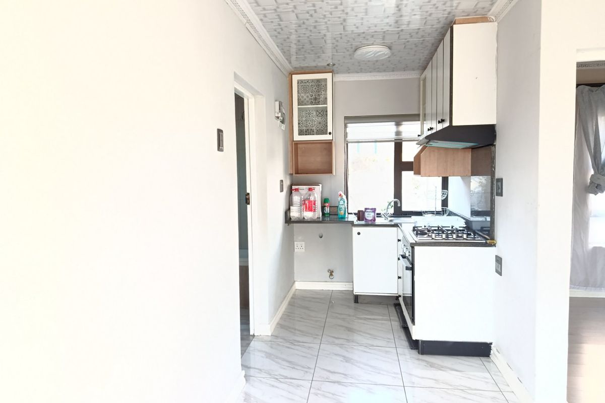 A compact kitchen featuring tiled flooring, built-in cabinetry with gas hob and oven, and a functional sink area requiring minor finishing touches.