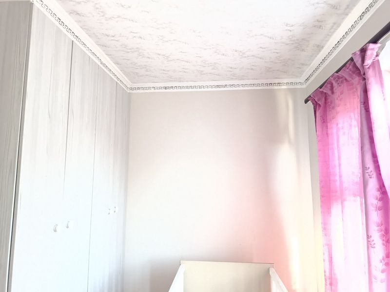 A bedroom interior featuring built-in wardrobes and decorative ceiling detailing, offering a clean and neutral space ready for personalization.
