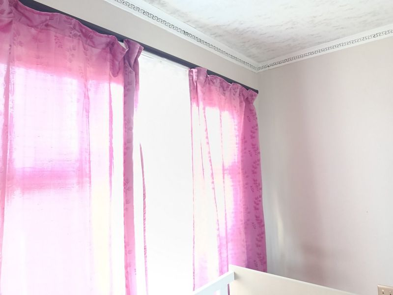 A bedroom corner featuring decorative ceiling cornicing and window treatments.