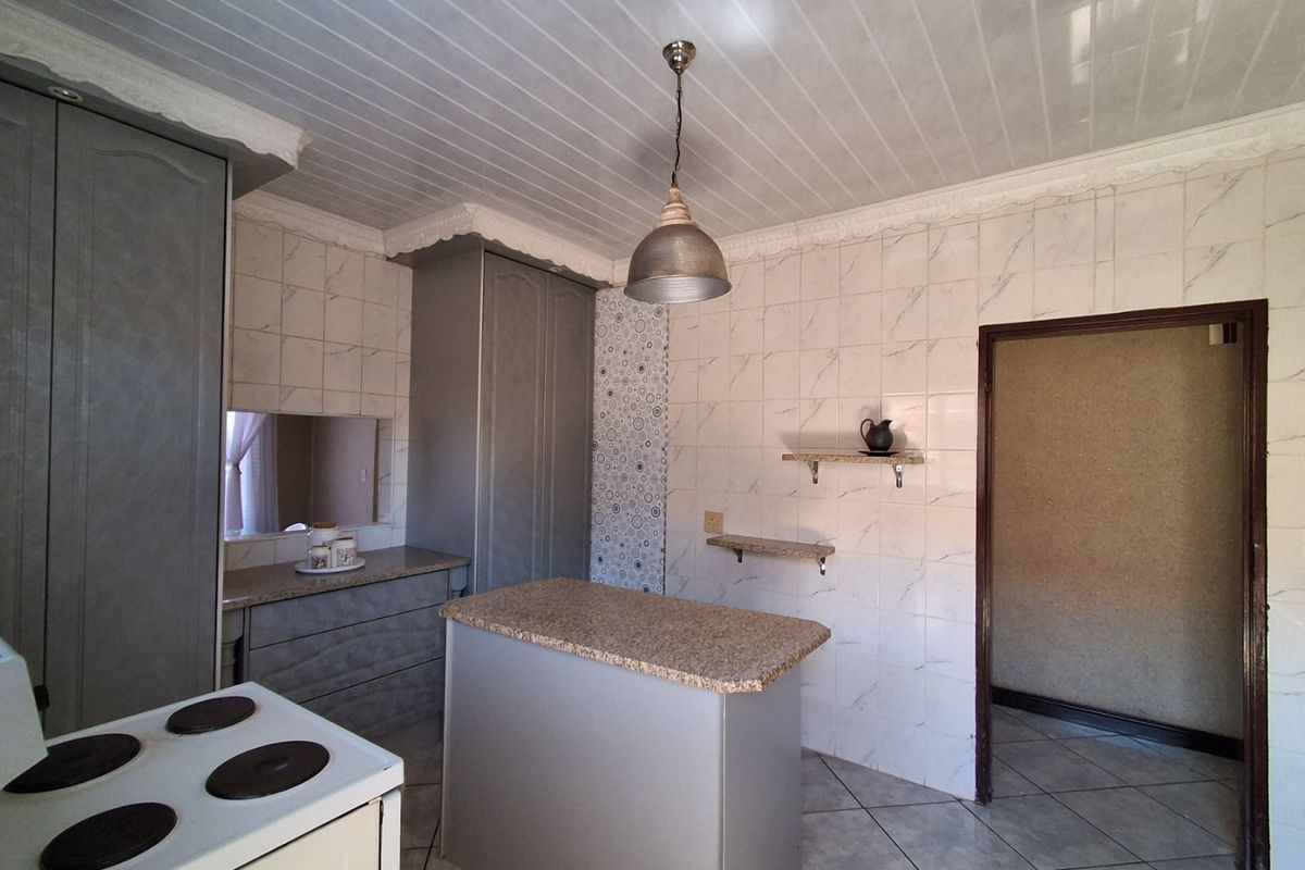 A functional kitchen featuring built-in cabinetry, granite countertops, tiled wall finishes, and an electric stove, offering a practical layout for daily use.