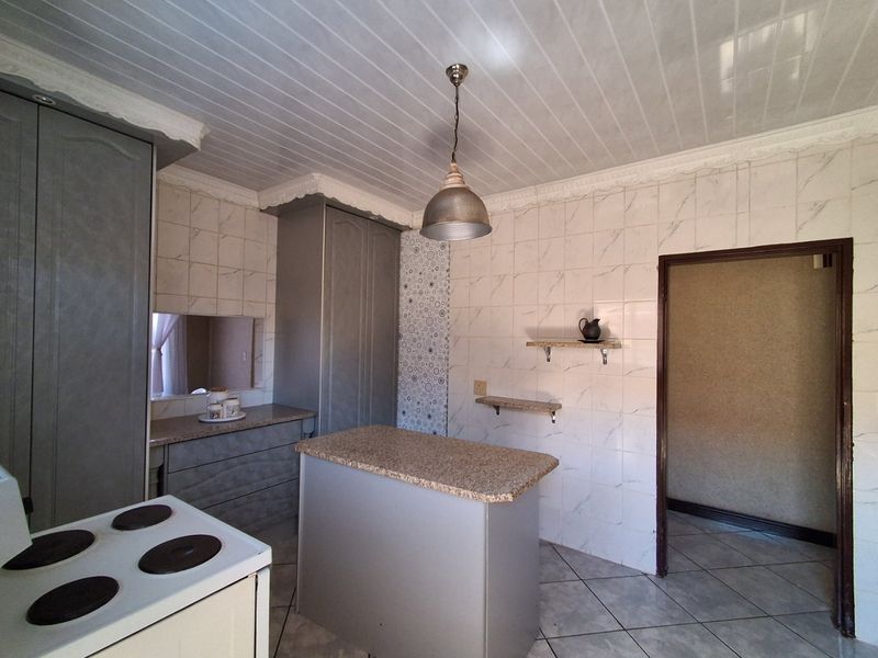 A functional kitchen featuring built-in cabinetry, granite countertops, tiled wall finishes, and an electric stove, offering a practical layout for daily use.