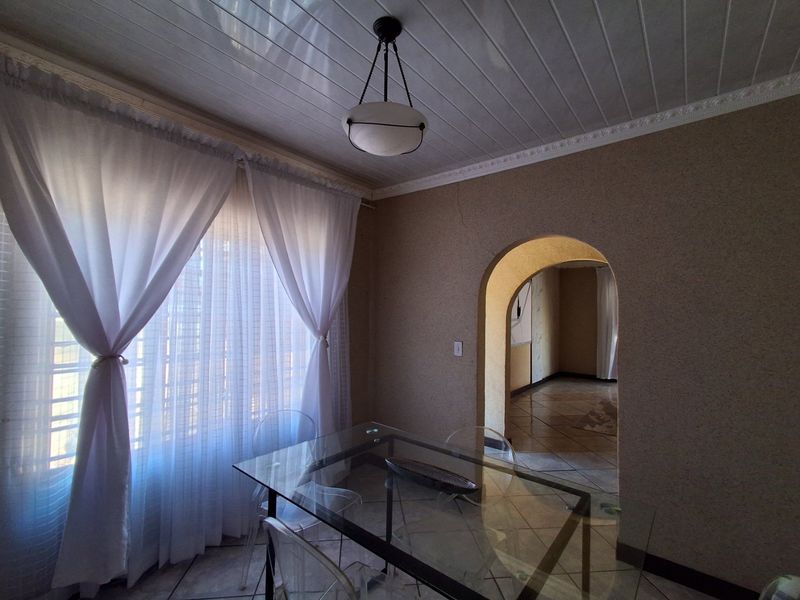 Dining area featuring tiled flooring, textured walls, decorative ceiling molding, and an arched doorway leading to an adjacent room.