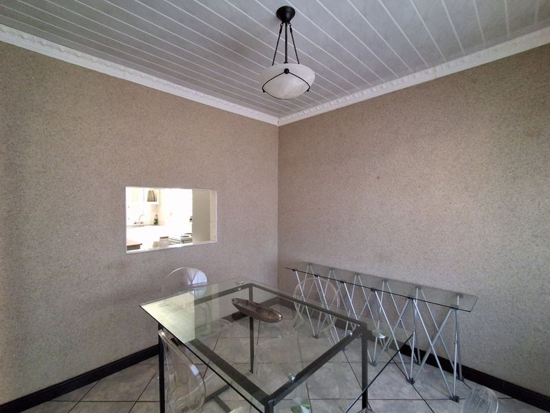 Dining room featuring tiled flooring, decorative ceiling cornice, and a convenient serving hatch connecting to the kitchen area.