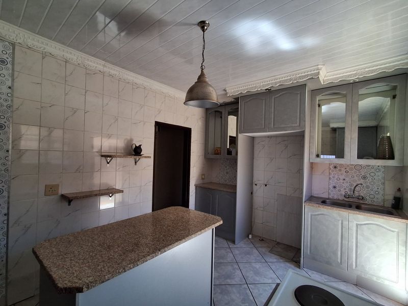A dated kitchen featuring granite countertops, built-in cabinetry, and tiled finishes, offering a functional layout ready for modernization and cosmetic updates.
