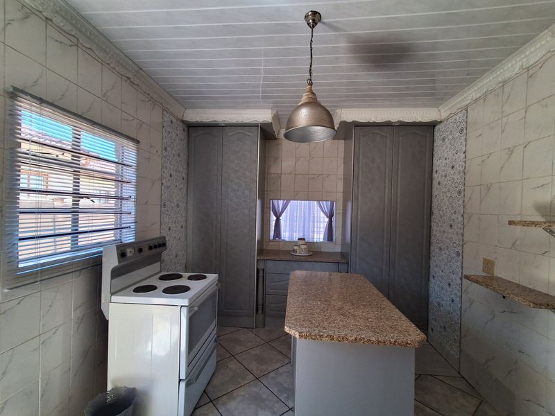 A functional kitchen featuring built-in cabinetry, granite countertops, a freestanding stove, and tiled finishes throughout.
