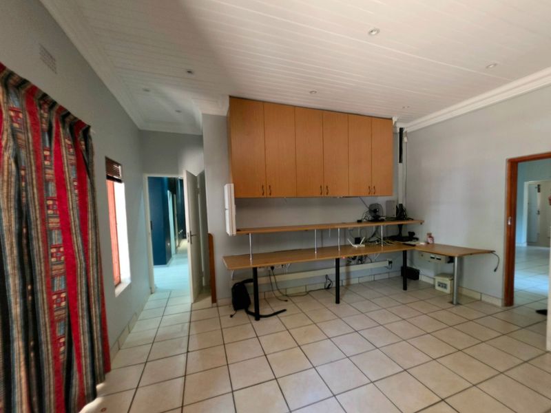 A functional home office space featuring built-in cabinetry, a long desk workstation, tiled flooring, and recessed ceiling lighting.